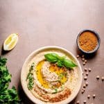 Bowl of hummus with lemon with chickpeas, spices, and herbs.
