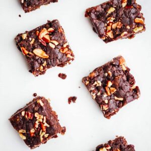 Six date bars topped with chopped pecans.