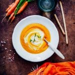 Bowl of healthy carrot ginger soup with coconut cream swirl.