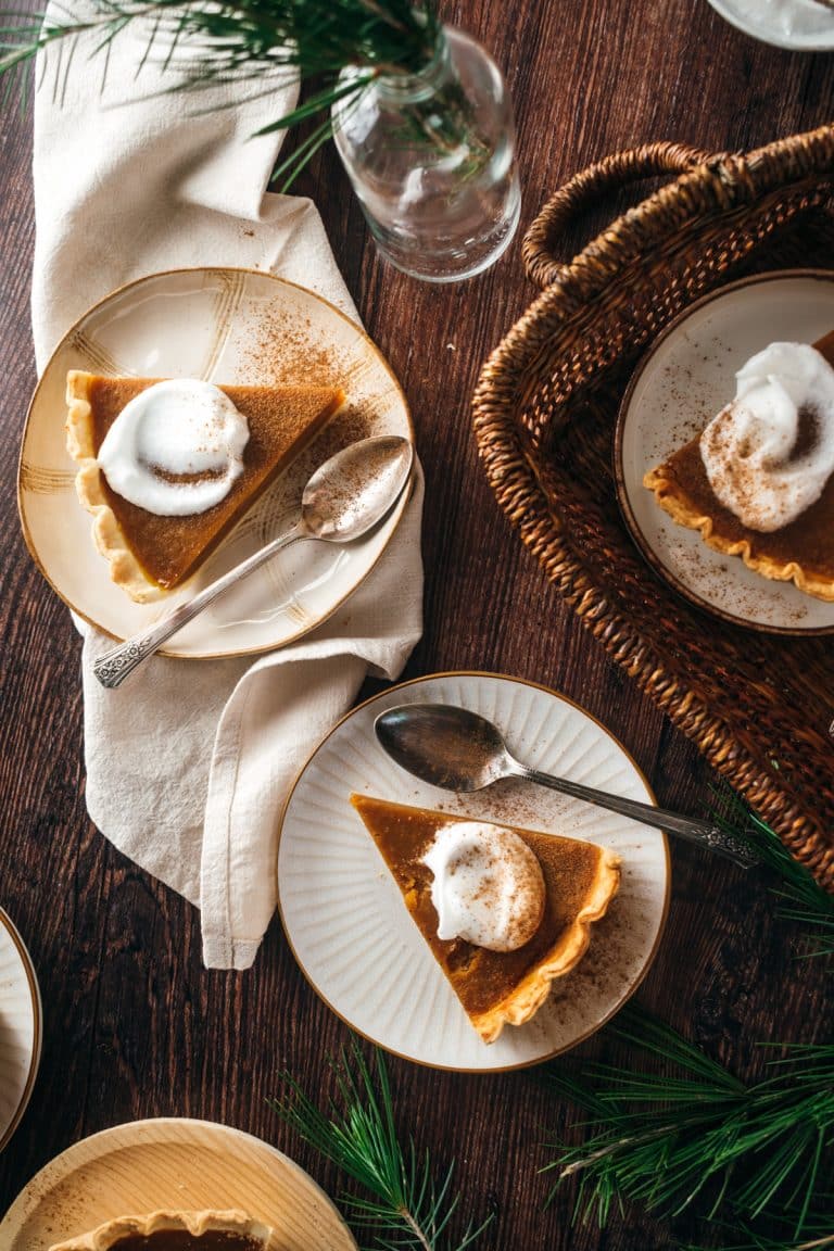 Three pieces of pumpkin pie with whipped cream on top.