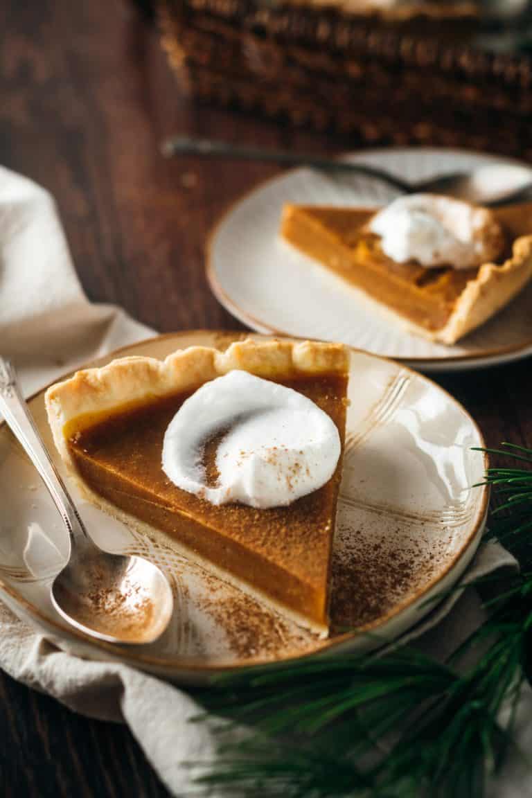 Two pieces of pumpkin pie with whipped cream.