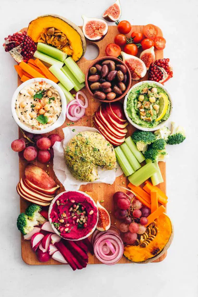 A cutting board with a variety of vegan fruits and vegetables.