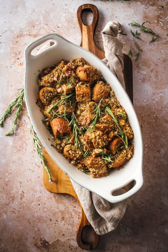 Vegan stuffing in a white platter on a wood cutting board.
