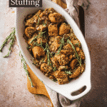 Vegan stuffing in a white platter on a wood cutting board.