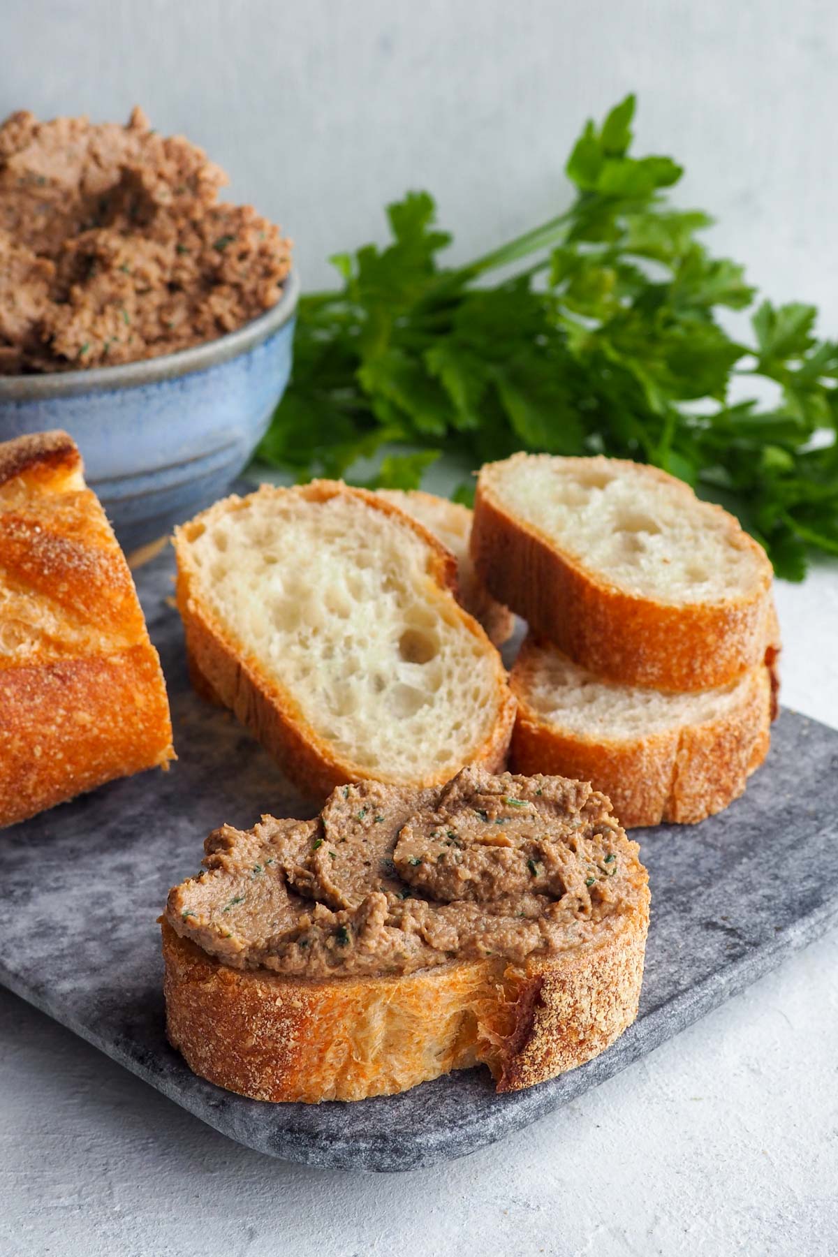 A vegan recipe of tahini spread served with bread and topped with fresh parsley, perfect for a holiday gathering.