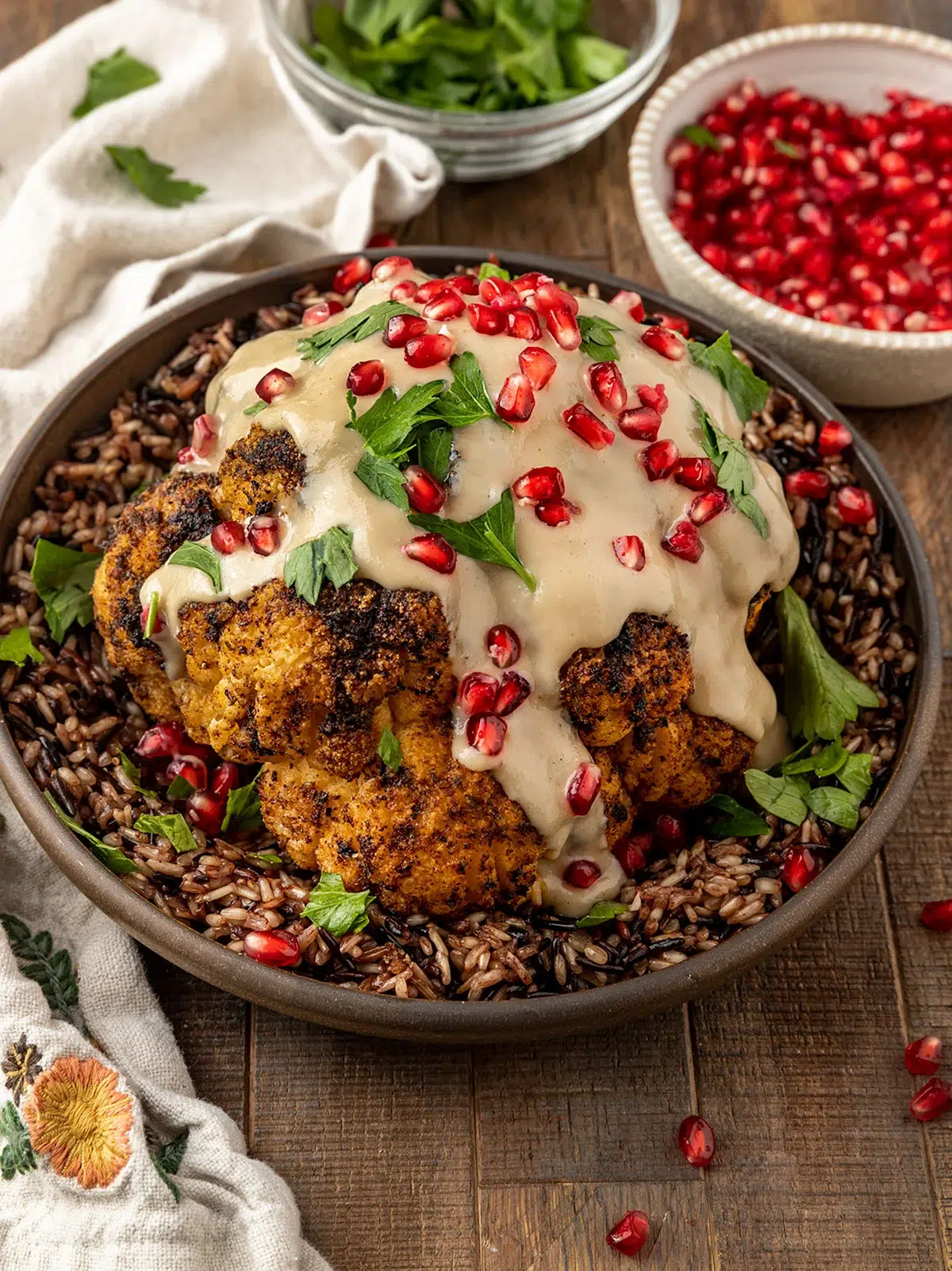 A vegan holiday recipe of roasted cauliflower with pomegranate sauce beautifully plated.