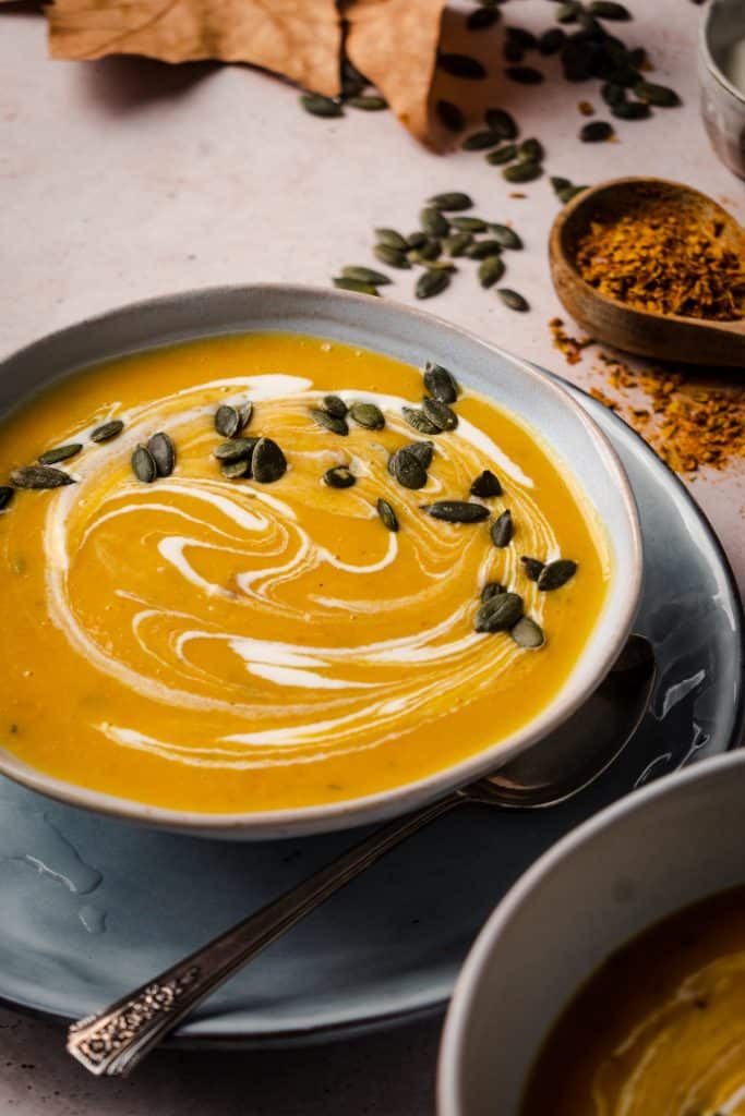 Angled photo of butternut squash soup with pumpkin seeds on top.