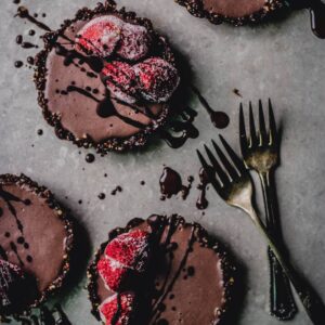 A group of vegan chocolate cheesecakes with strawberries on top.