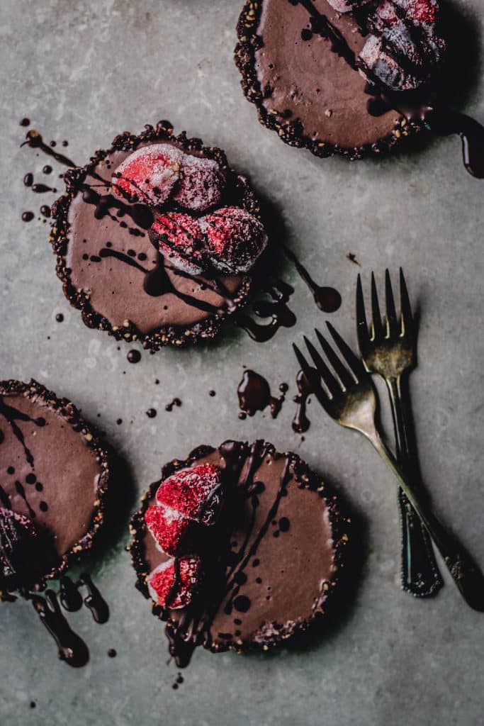 A group of vegan chocolate cheesecakes with strawberries on top.