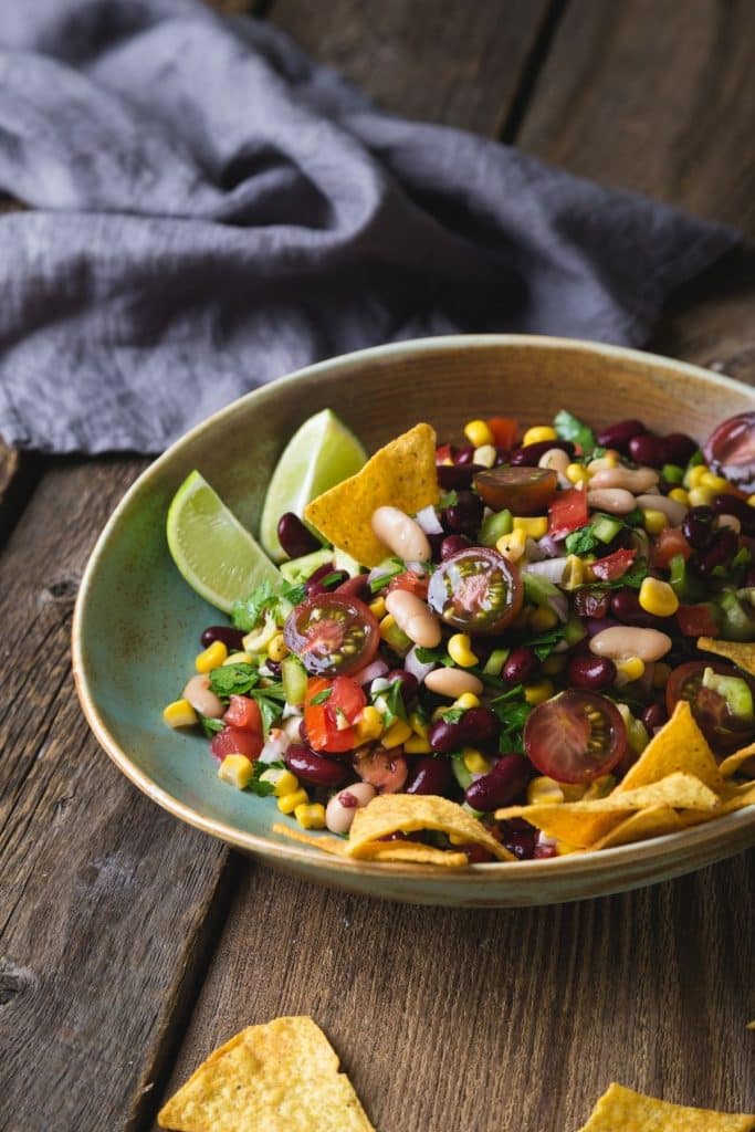 Close up bowl of Cowboy Caviar with a gray napkin and lime wedges