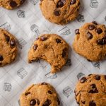 Several pumpkin chocolate chip cookies on parchment paper.