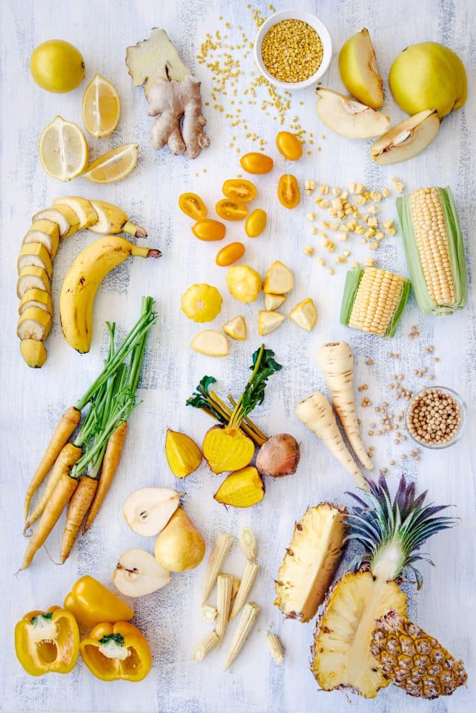 Many different yellow foods on a white surface.