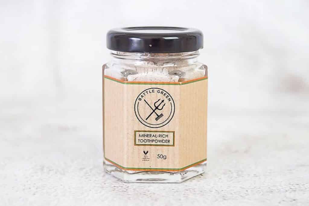 Zero-waste toothpaste powder in a glass jar with a black metal lid. 