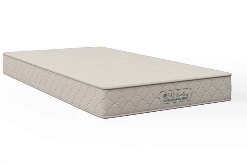 Creamy colored crib mattress pictured at an angle.