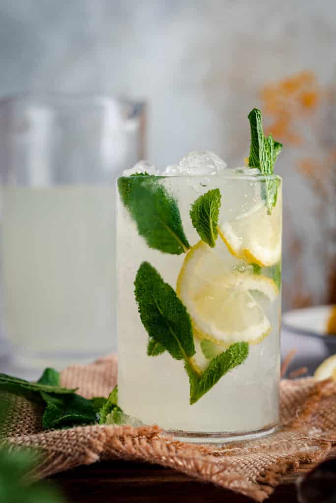 Glass of lemonade with fresh mint and lemon wedges.