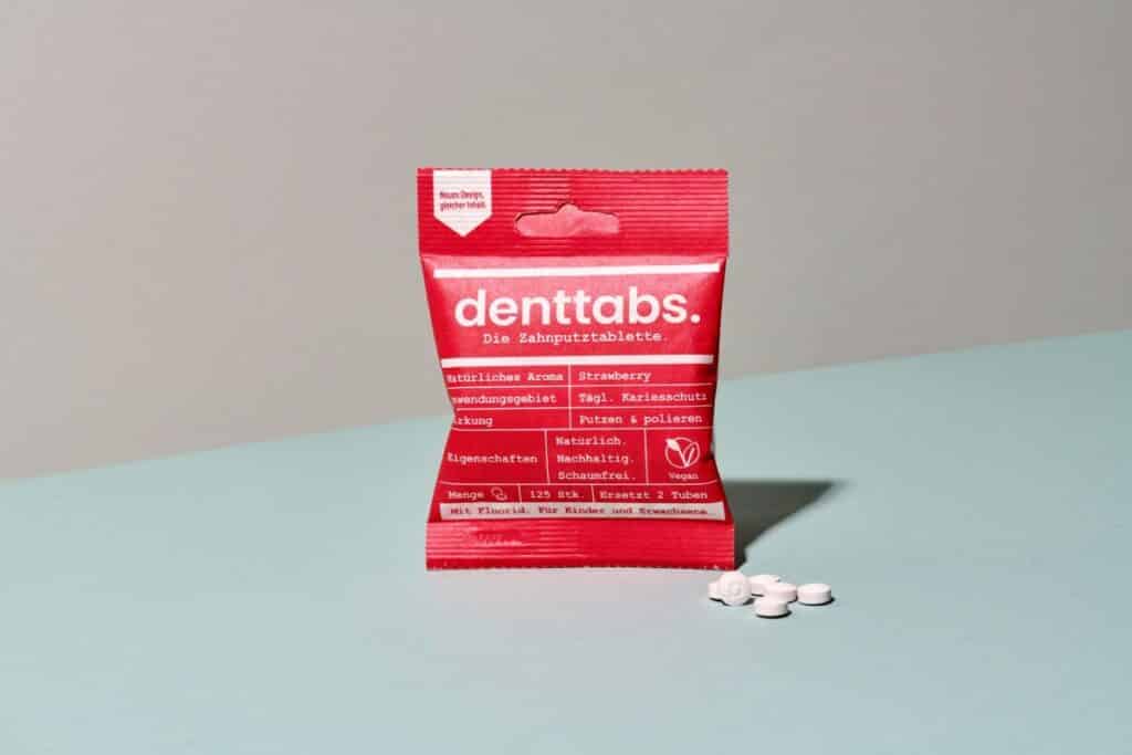 Toothpaste tablets in a compostable red package.