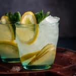 Close up glass of ginger lemonade with fresh lemon wedges.