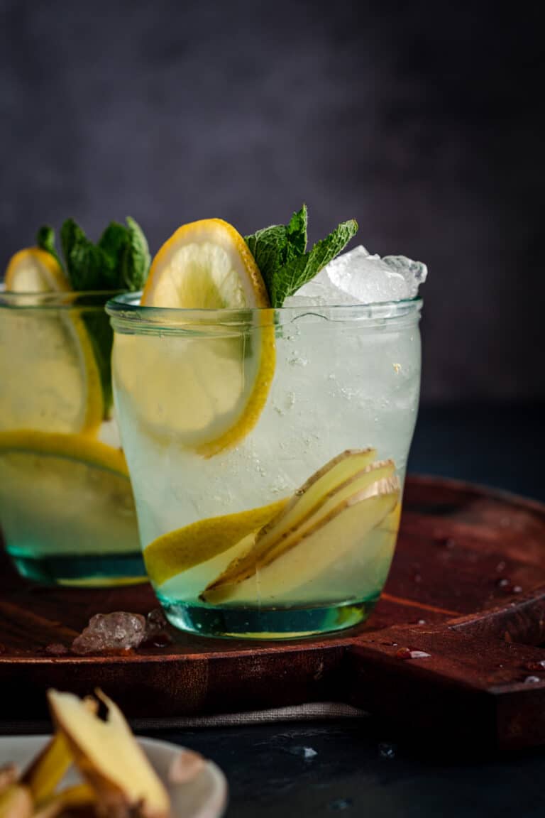 Close up glass of ginger lemonade with fresh lemon wedges.