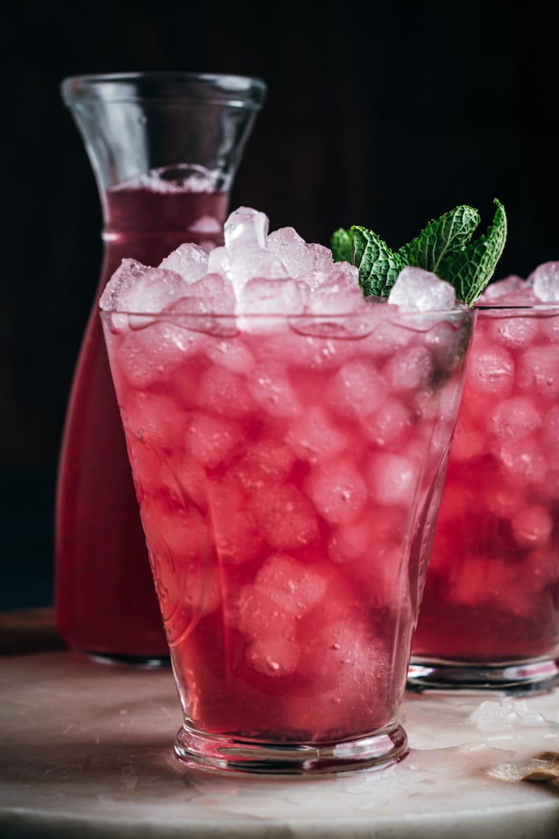 Up close look at bright pink iced cranberry lemonade in a clear glass cup. 