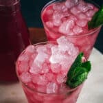 Top angle view of two cups of iced cranberry lemonade with fresh sprig of mint.