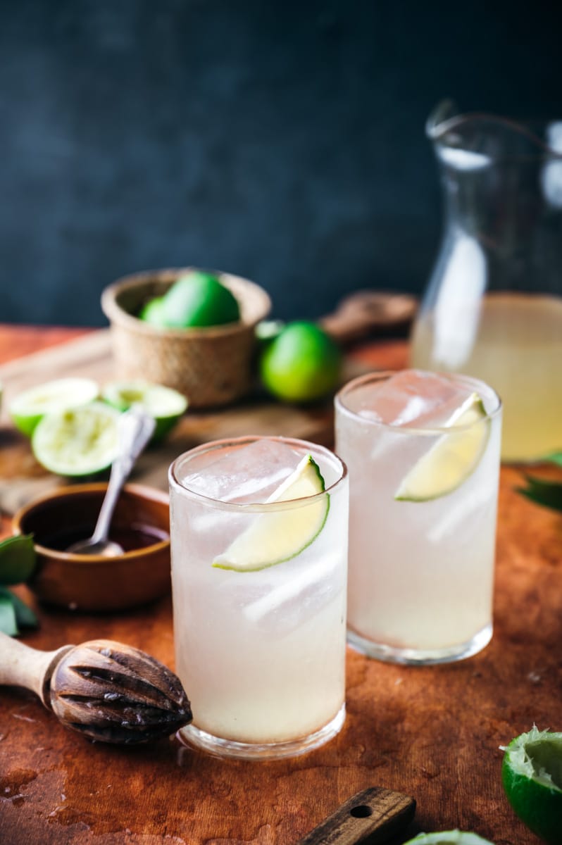 Two cups of limeade on a wooden surface.