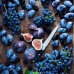 Blue grapes, blue berries, blue figs, blue honeysuckle and a knife.