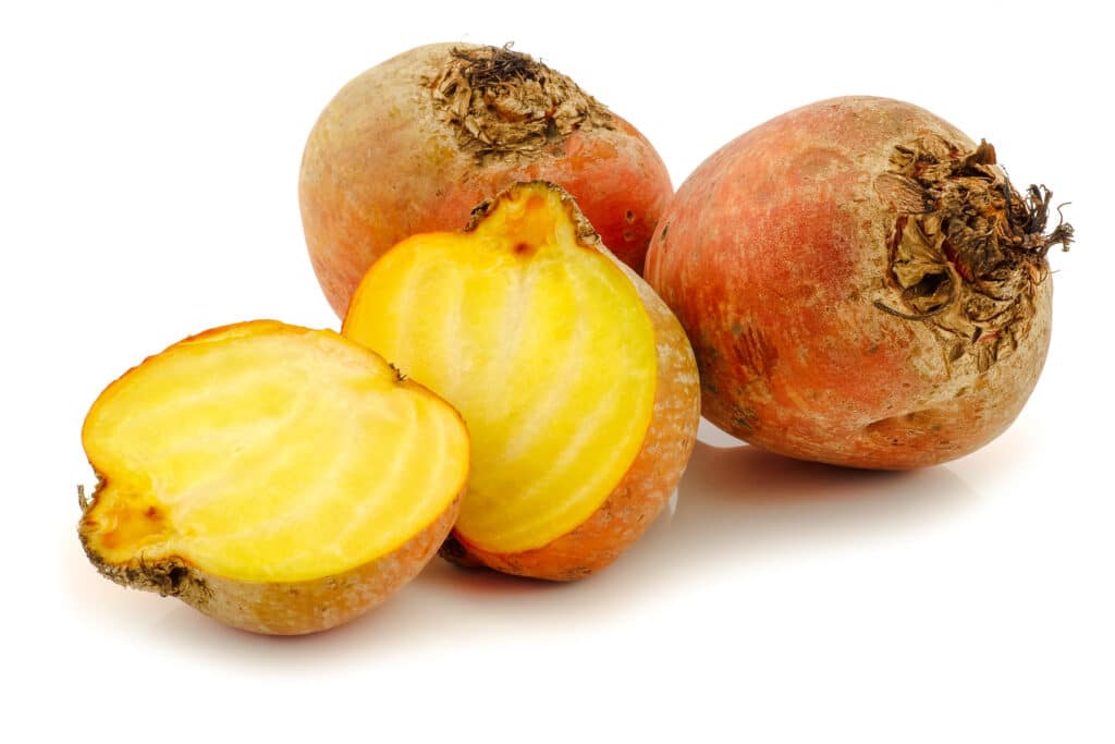 Three large golden beets with one sliced in half.