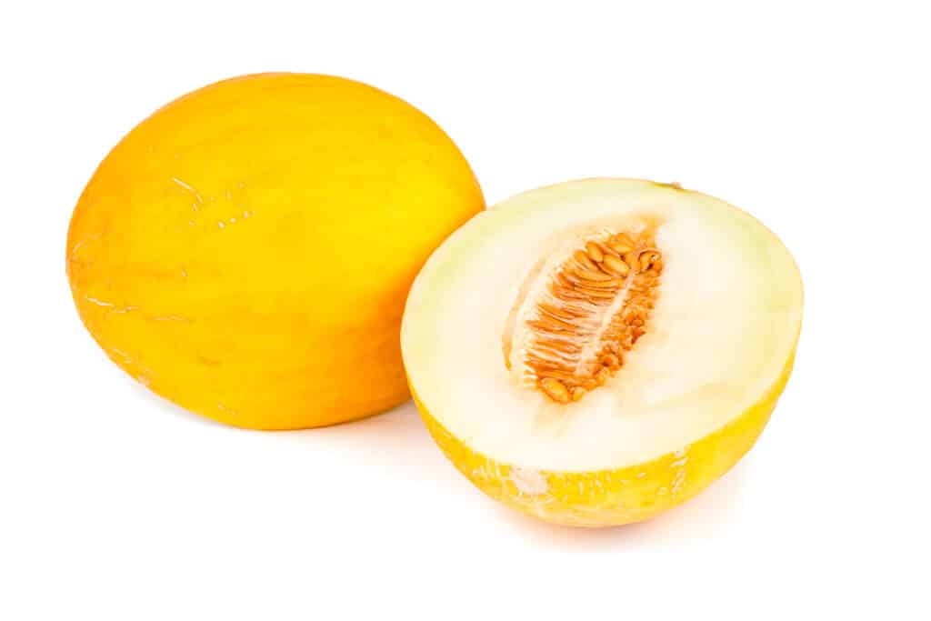 One and a half yellow melons on a white surface.