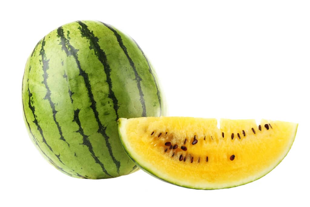 Large yellow watermelon with a large slice showing its black seeds.