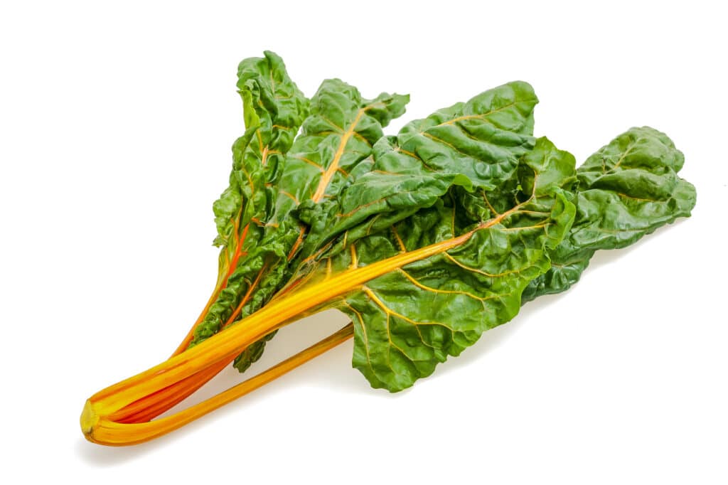 A bunch of yellow-orange Swiss chard on a white surface.