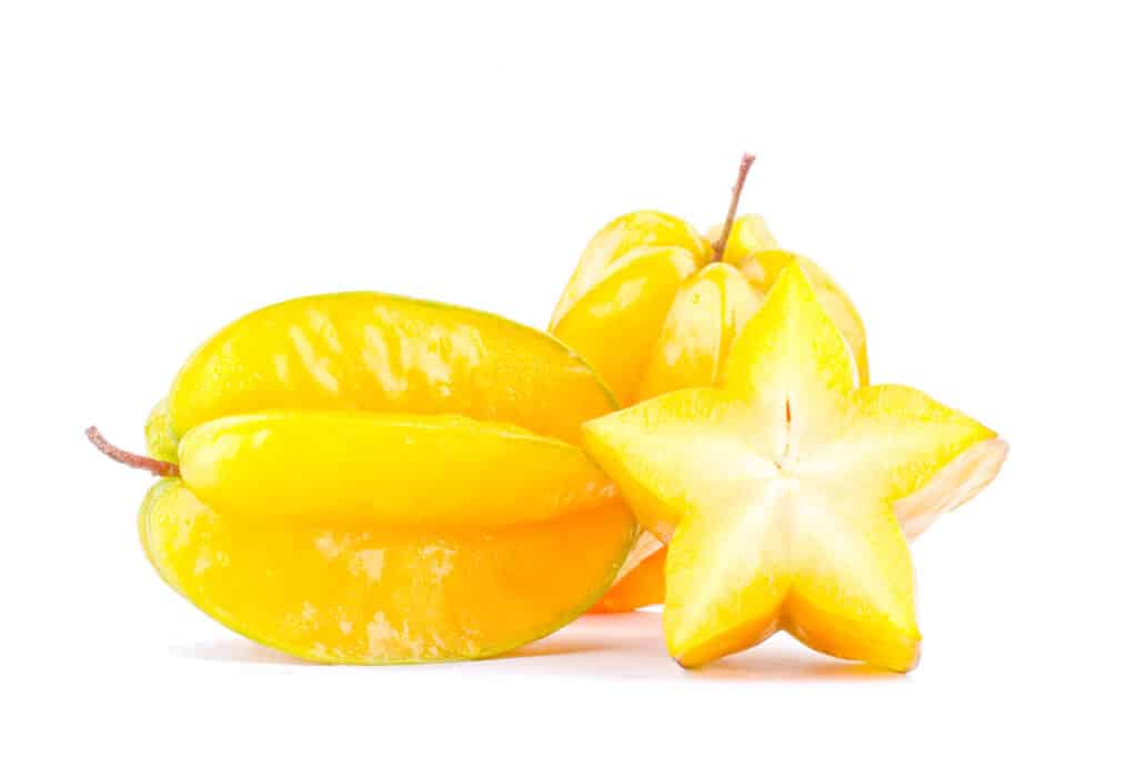 Two whole star fruits with a slice cut in front. 