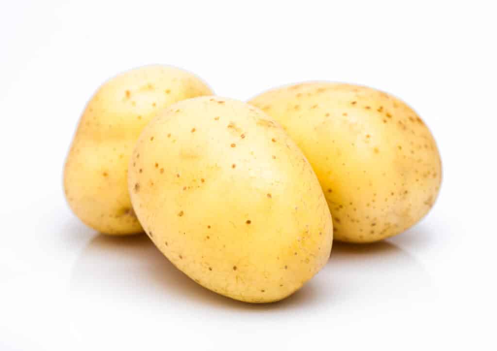 Three yellow potatoes on a white surface.