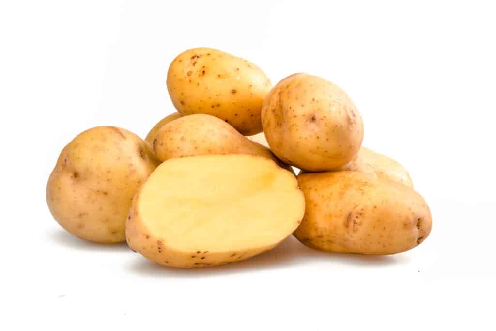 Pile ofYukon gold potatoes on a white surface.