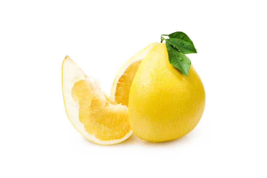 Large yellow citrus fruit with a green leaf.