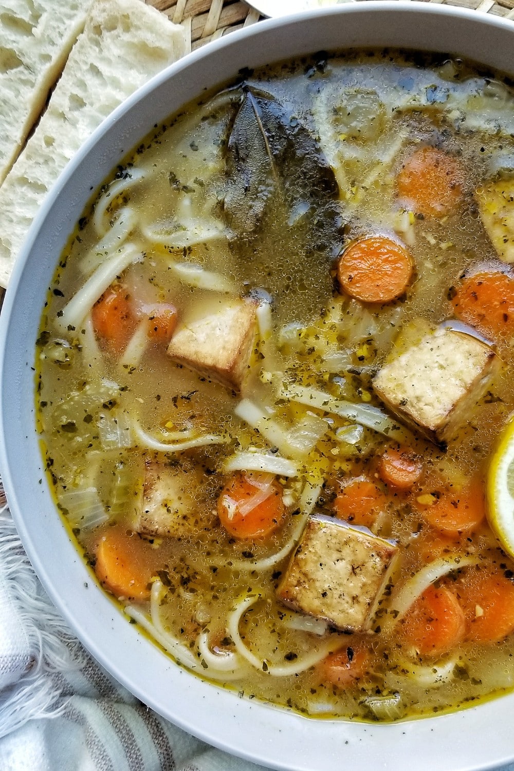 A bowl of chicken noodle soup with carrots and tofu.