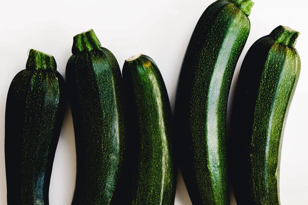 A group of black zucchini (zucchetti, courgettes) on a white background