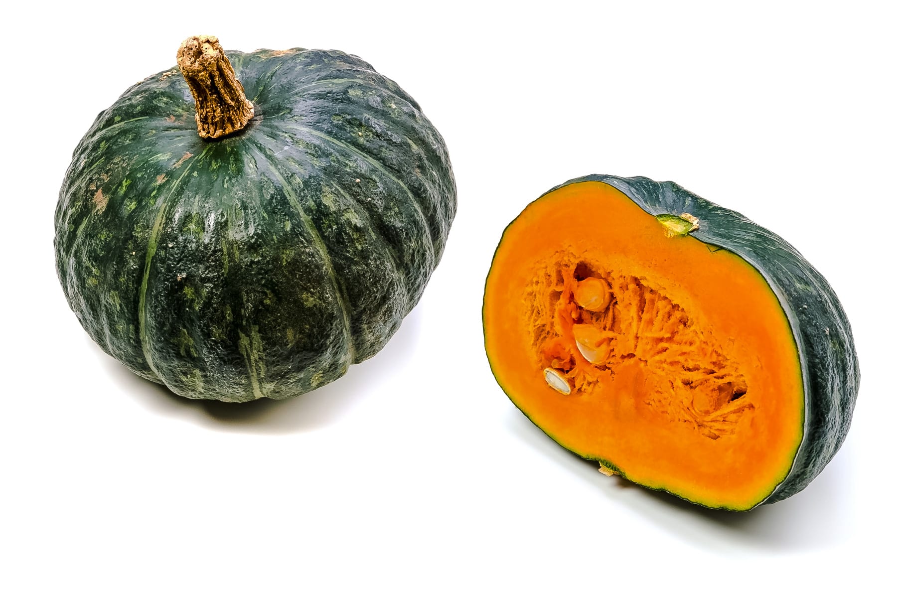 Whole kabocha squash with one cut in half next to it.