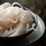 Close up side view of cooked rice noodles.