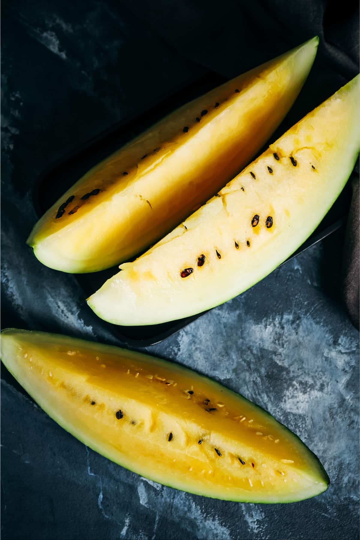 Three large wedges of bright yellow watermelon.