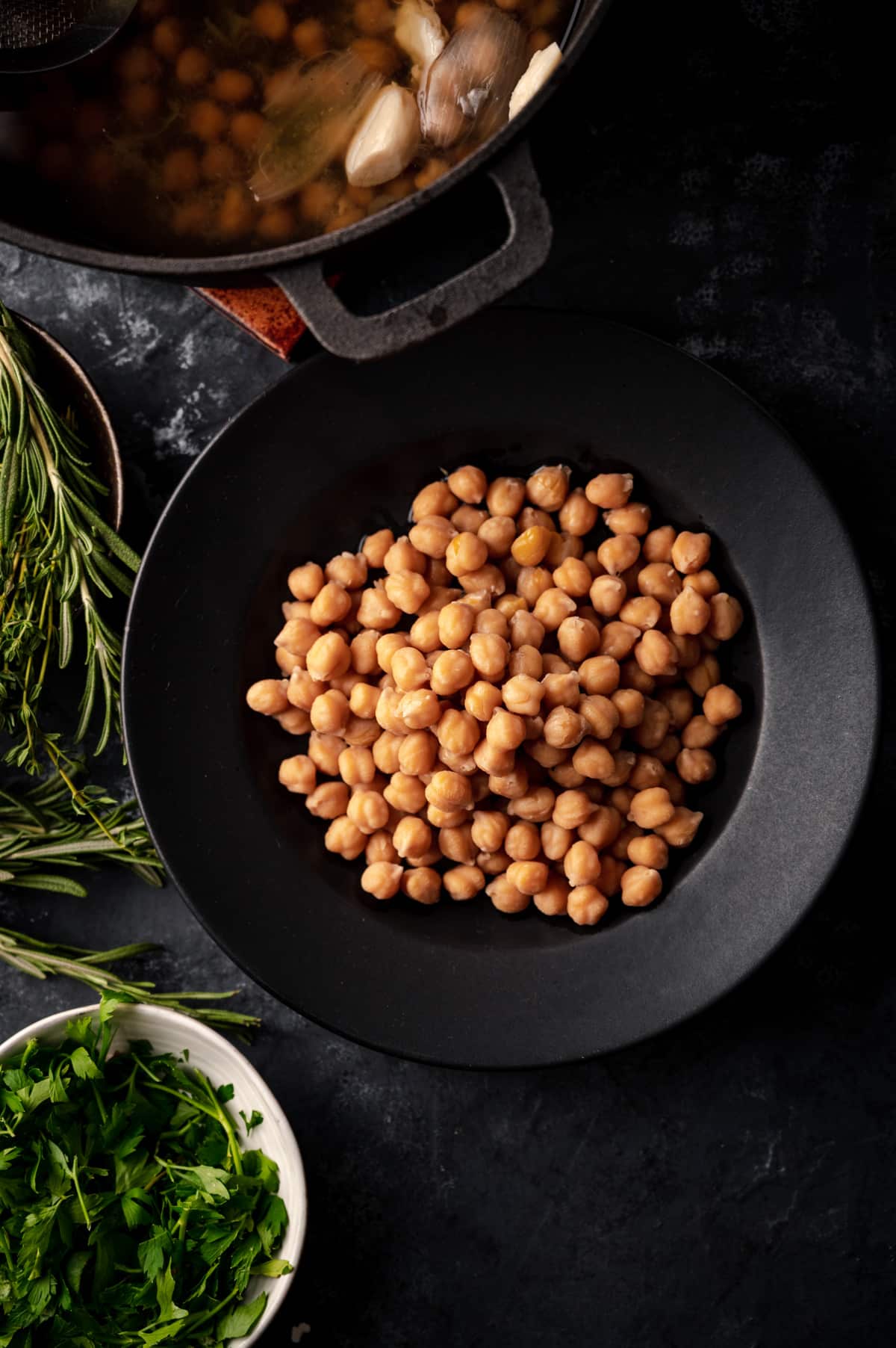 Close up of cooked chickpeas with fresh herbs on the side.