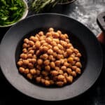 Black plate filled with cooked chickpeas.