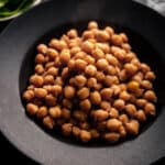 Close up of black plate with cooked garbanzo beans.