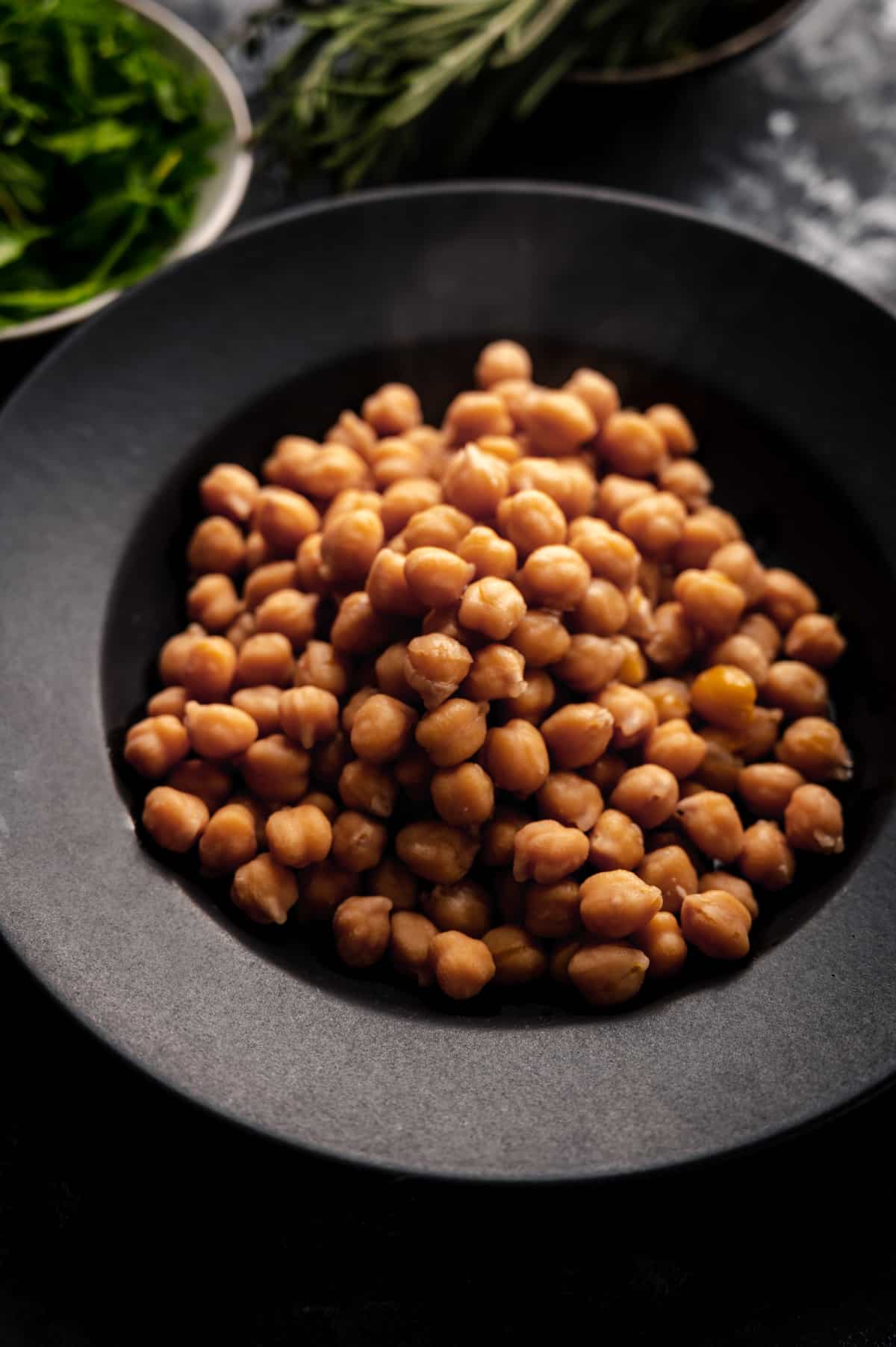 Close up of black plate with cooked garbanzo beans.
