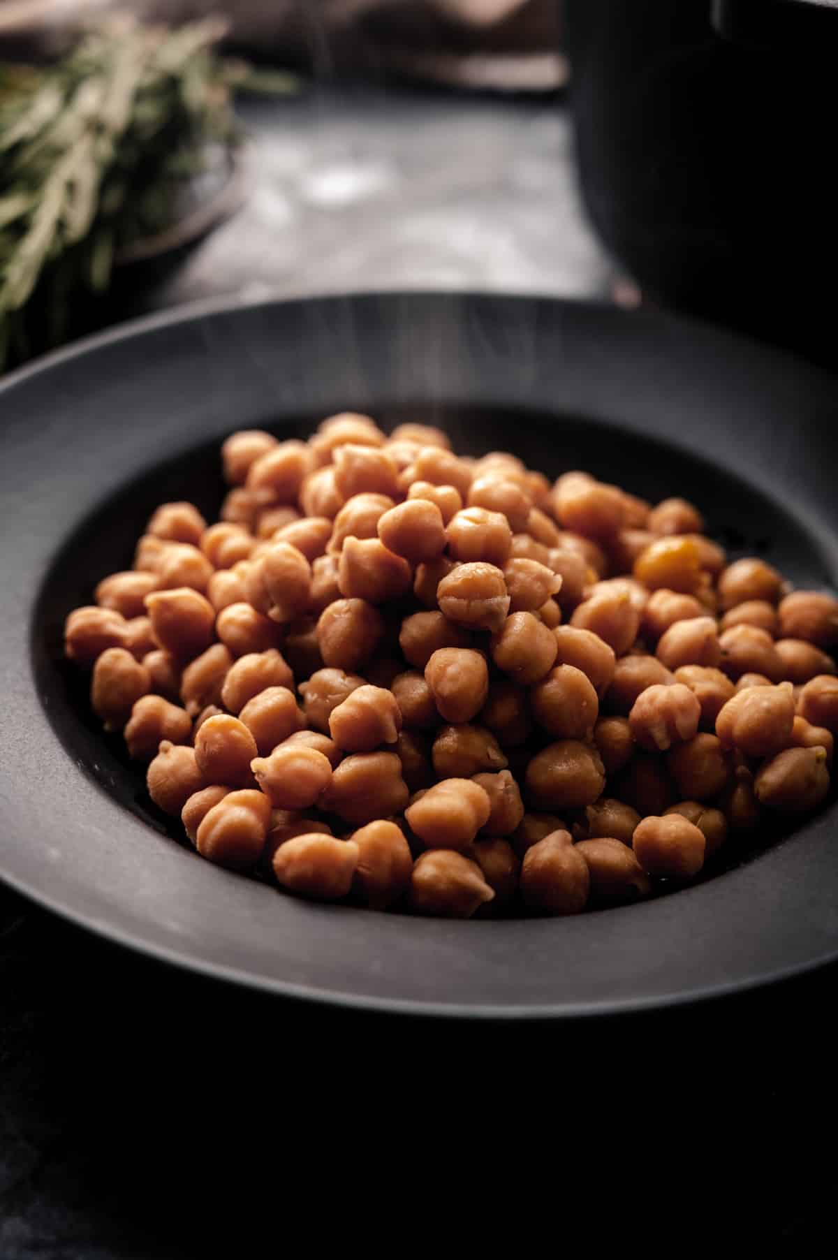Angle shot of freshly cooked chickpeas with the cooking pot behind it.