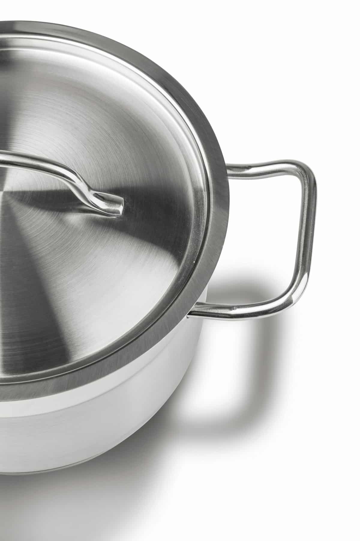 Angle view of half of a stainless steel pot with stainless steel lid. 