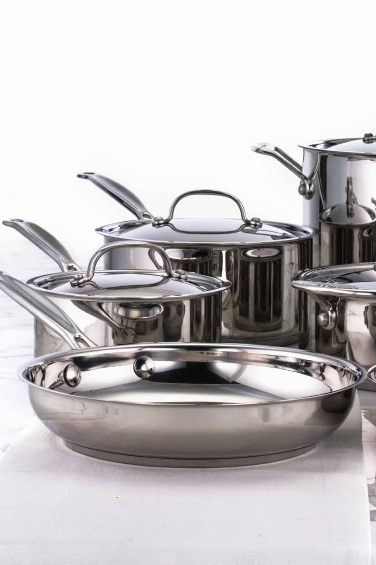 Stainless steel frying pan in front of other stainless steel pots. 