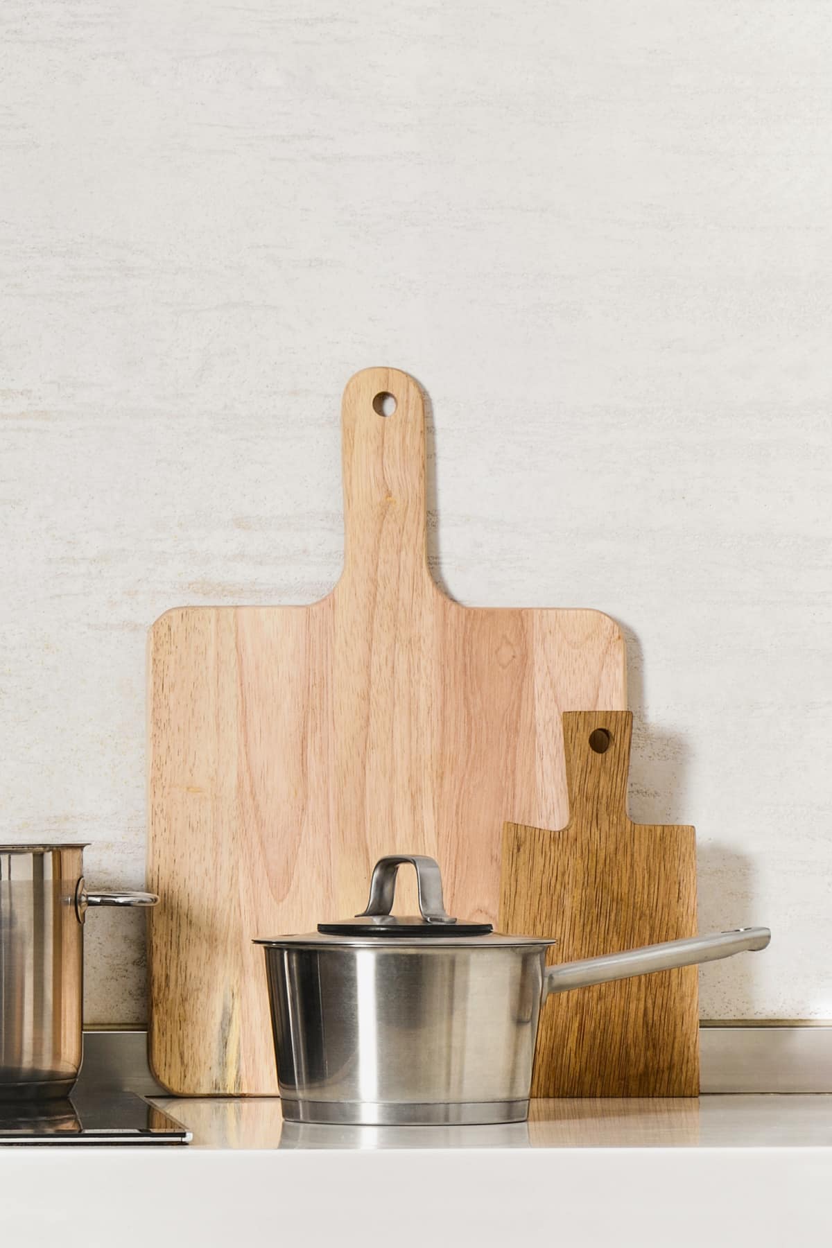 Stainless steel saucepan with two wooden cutting boards behind it.