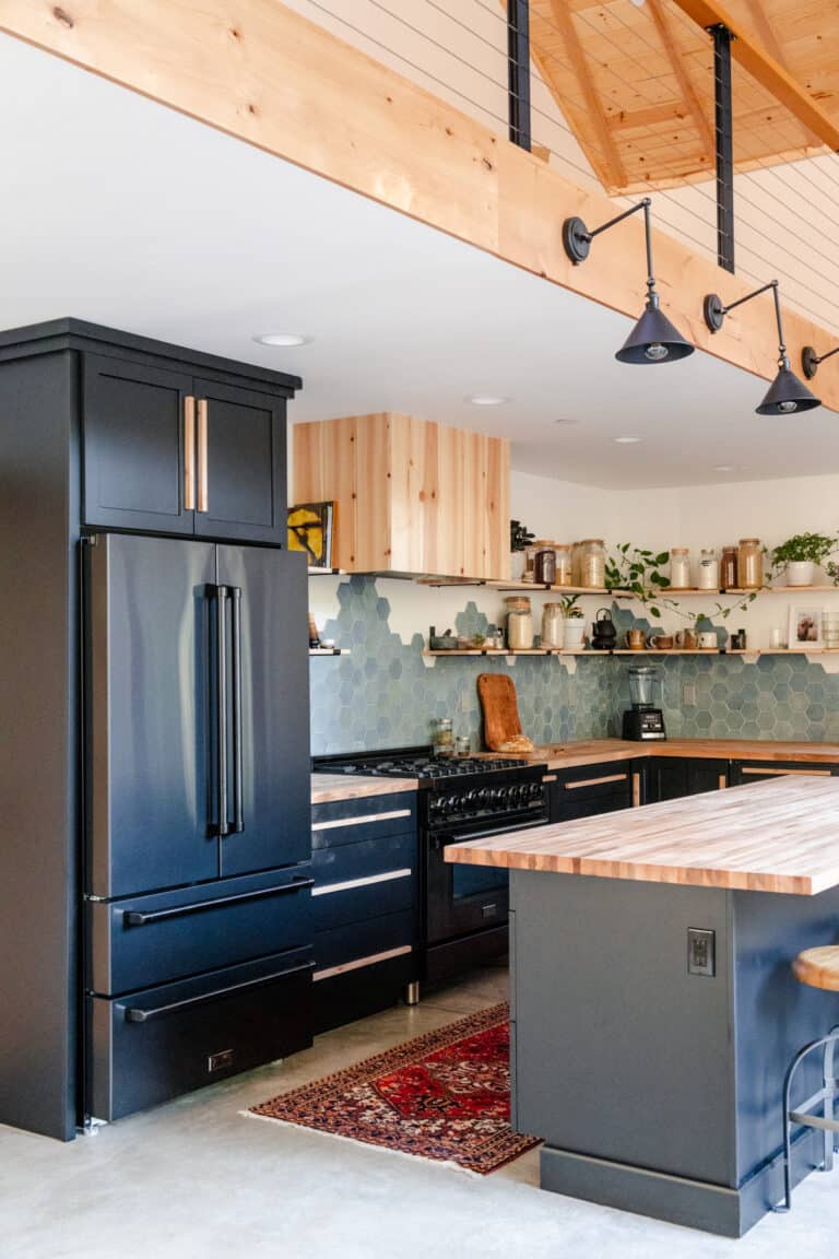 Raepublic kitchen featuring Black Stainless Steel Counter-Depth Fridge, 36" Range, and Range Hood Insert cladded in wood.