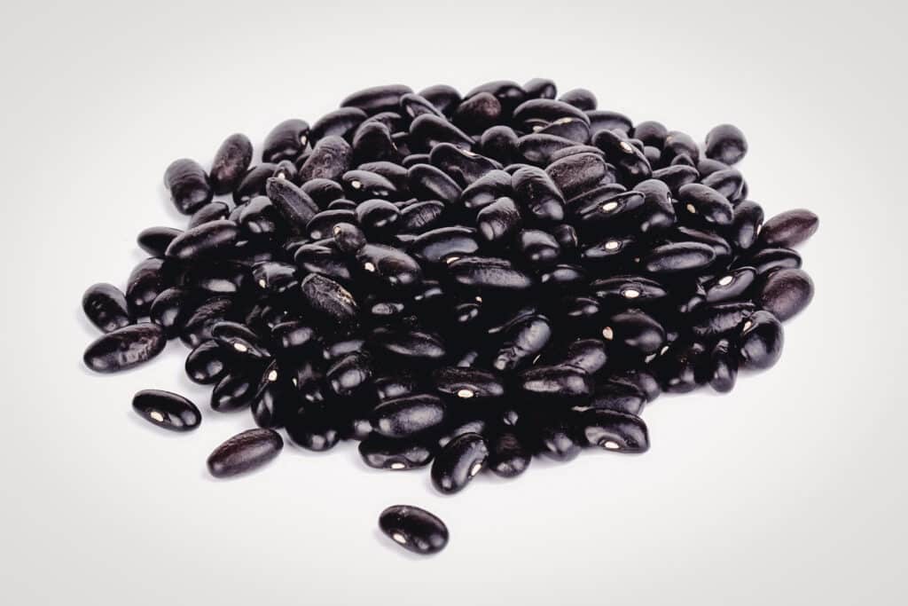 Pile of black valentine beans on a white surface.