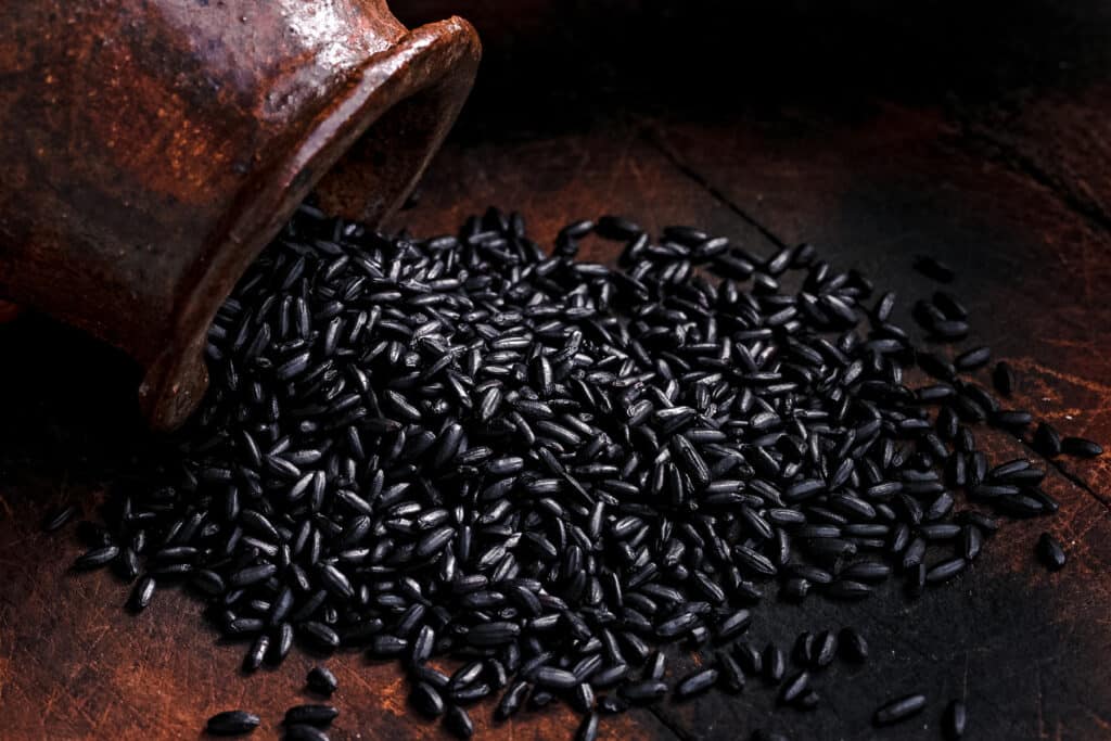 Dark wooden table covered in a pile of black Forbidden rice.